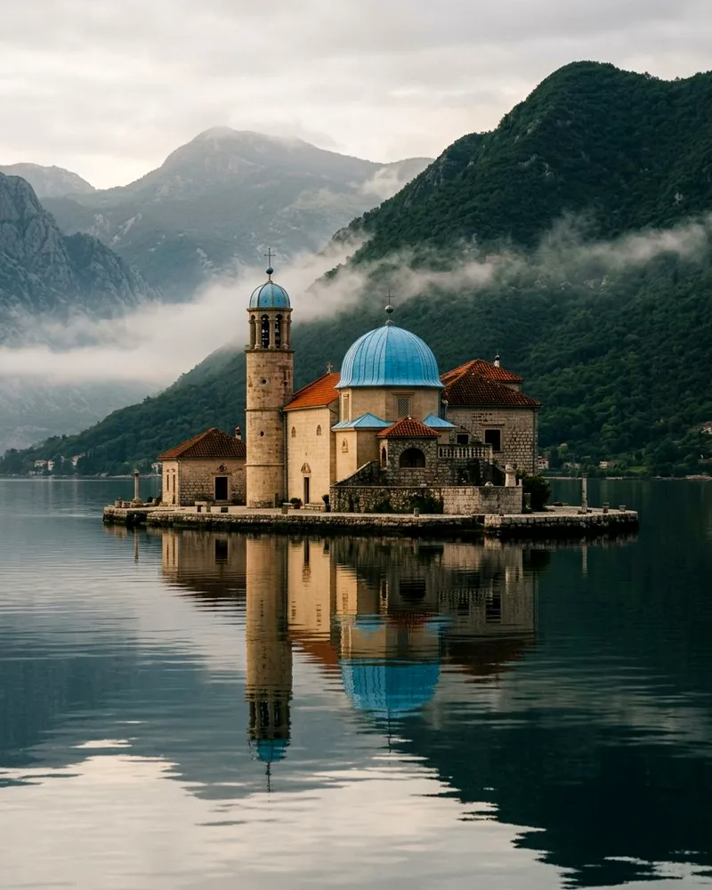 Our Lady of the Rocks church on its islet, reflected in still bay water